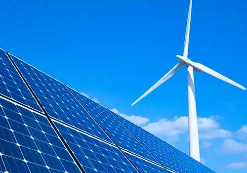 An image of solar panels with a wind turbine in the background.
